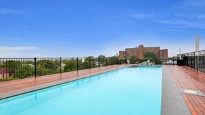 A rooftop swimming pool with a clear blue sky and distant buildings. - Ultimate 2-Bed Apartment in Surry Hills - Ultimate Convenience (Surry Hills)
