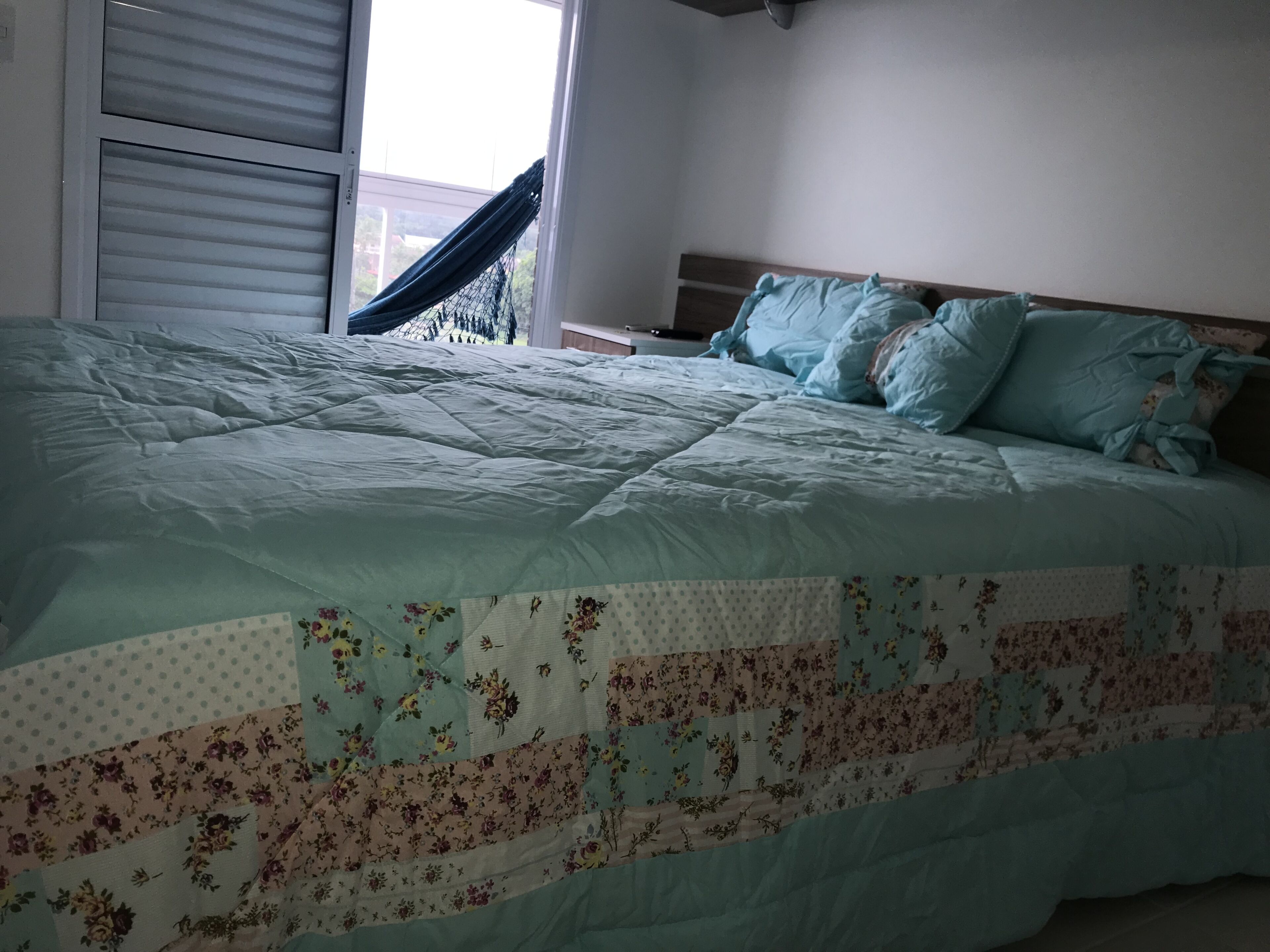 Una camera da letto con un letto grande, una finestra con tende e un'amaca all'esterno.