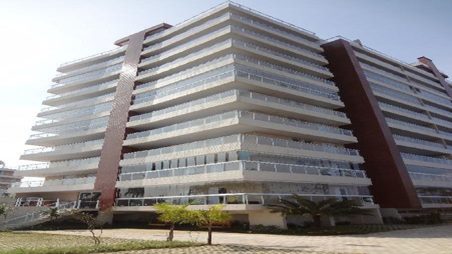 A multi-story hotel with a modern architectural design, featuring balconies on each floor and a central courtyard with a small tree.