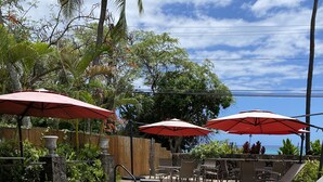 A pool with 'Royal Kahili' written on the water, surrounded by lounge chairs and red umbrellas.