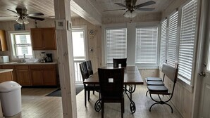 A spacious kitchen with wooden cabinets, a dining table with chairs, and a ceiling fan. - 3BR Beachfront Getaway – Behind Owner’s Home (Sylvan Beach)