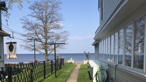 A pathway leading to a beach, flanked by a fence and potted plants. - 3BR Beachfront Getaway – Behind Owner’s Home (Sylvan Beach)