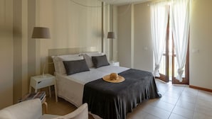 Een keurig opgemaakt slaapkamer met een bed, nachtkastjes, een stoel en een hoed op het bed.