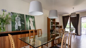 Een moderne eetruimte met een tafel met glazen blad, houten stoelen en hanglampen.