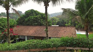 A building with a tiled roof, surrounded by lush greenery and palm trees. - HOUSE, FARM, SITE, VERY GREEN 60 KM FROM SPAULO  (Santa Isabel)