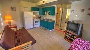 A compact living space with a kitchenette, a television, and a bed. - Oleander Beach Lodge - Four Condos for One Great Price (South Padre Island)