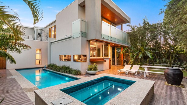 Une maison moderne à deux étages, dotée d’une piscine, d’un espace extérieur aménagé et d’un jardin bien entretenu.