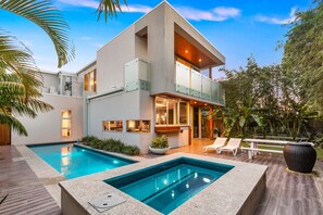 Une maison moderne à deux étages, dotée d’une piscine, d’un espace extérieur aménagé et d’un jardin bien entretenu.