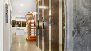 Un intérieur moderne avec un sol en béton poli, un escalier en bois et une cloison en verre.