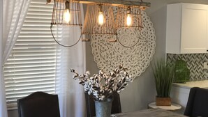 A dining area with a table, chairs, a vase with cotton plants, and a decorative wall piece. - Beautiful Updated/Decorated Quaint Cottage in the Heart of Fredericksburg (Fredericksburg)