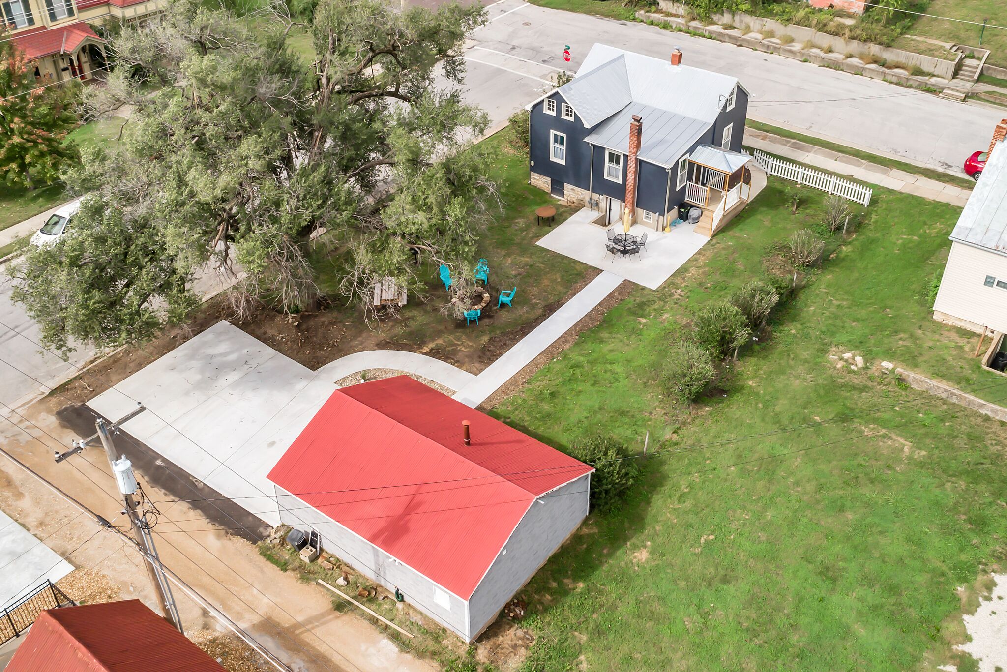 A residential property with a red-roofed building, a grey-roofed house, and a fenced yard.
