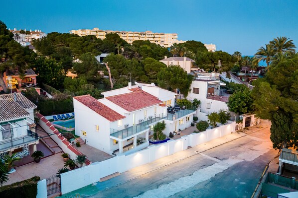 A coastal hotel with a red-tiled roof, multiple balconies, and a swimming pool.