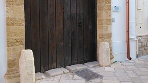 Una puerta grande de madera oscura con un marco de piedra arqueado, ubicada en un patio empedrado.