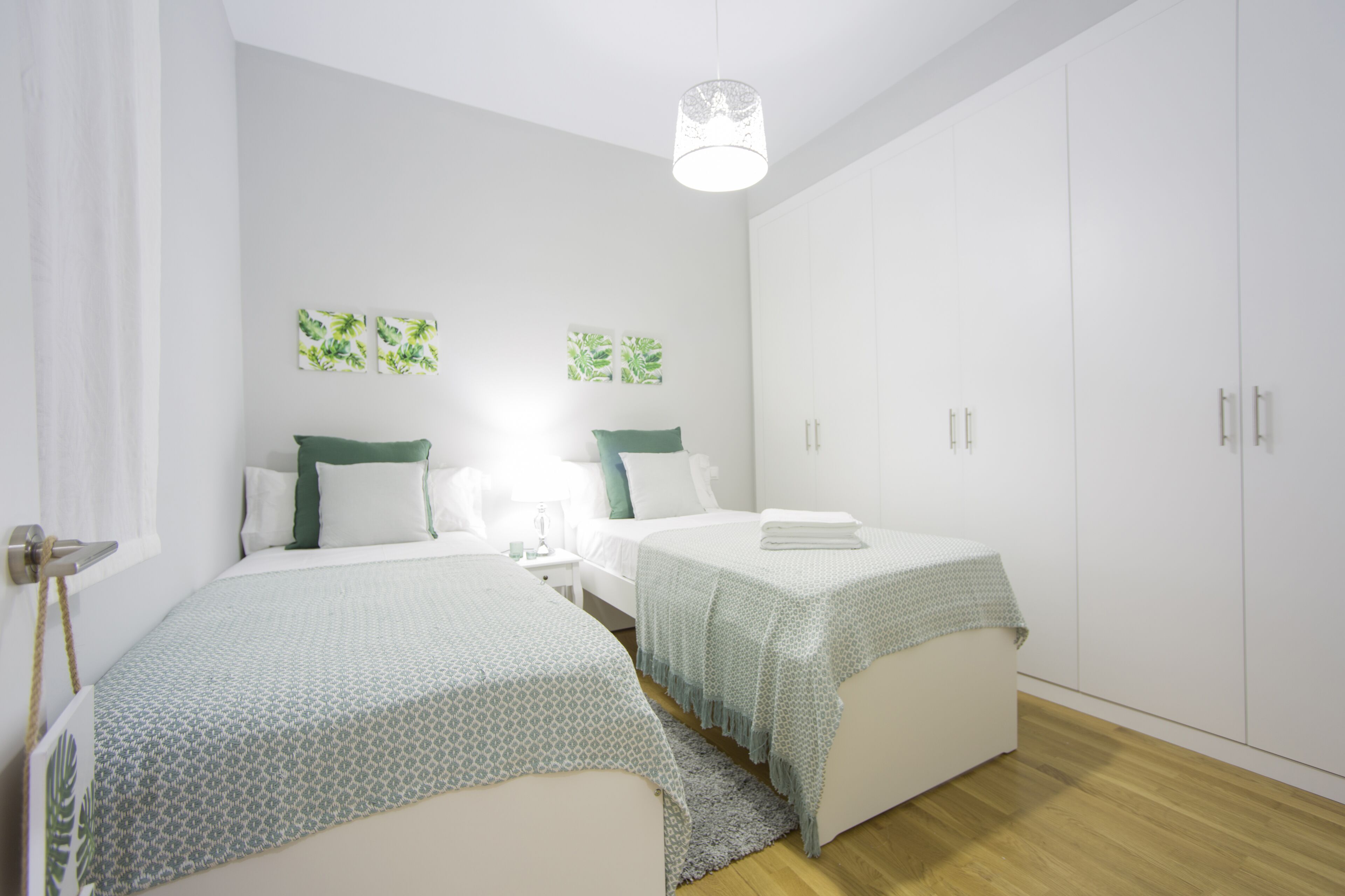 Een moderne slaapkamer met twee bedden, witte muren en een grote garderobe.