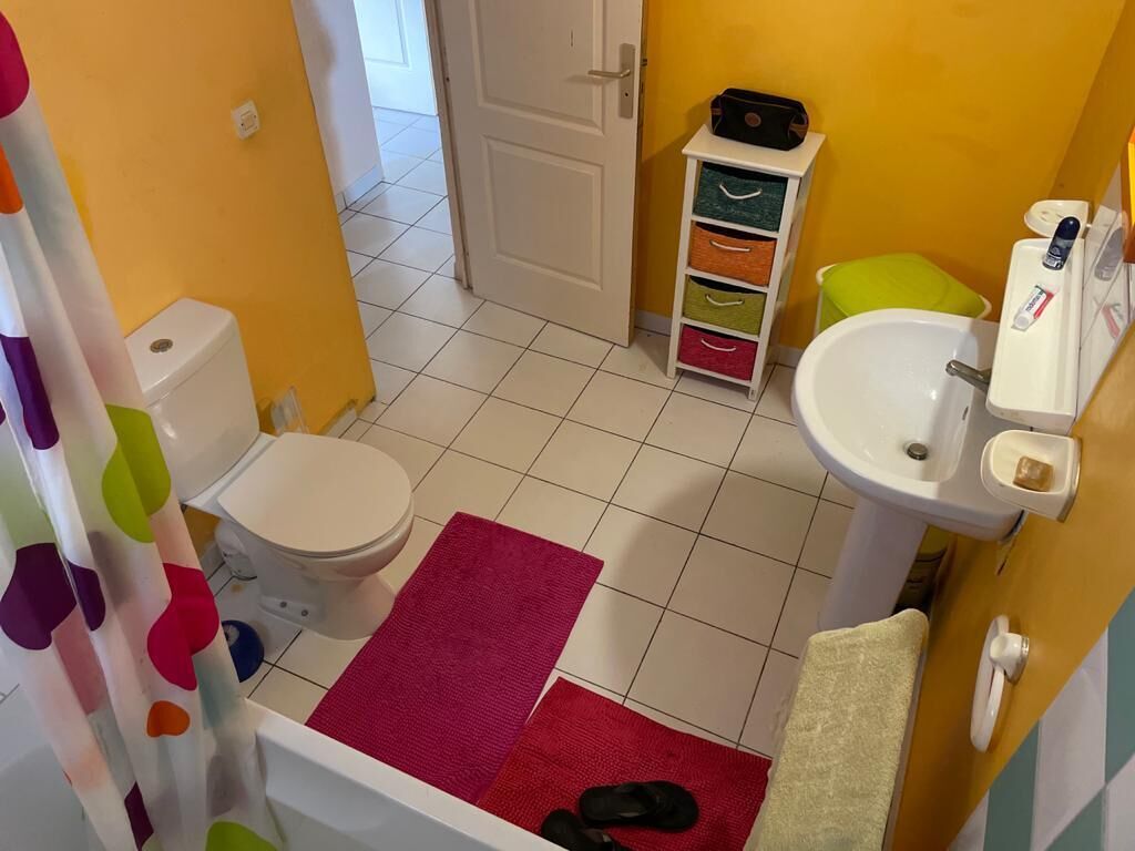 A small bathroom with a toilet, sink, and storage unit.