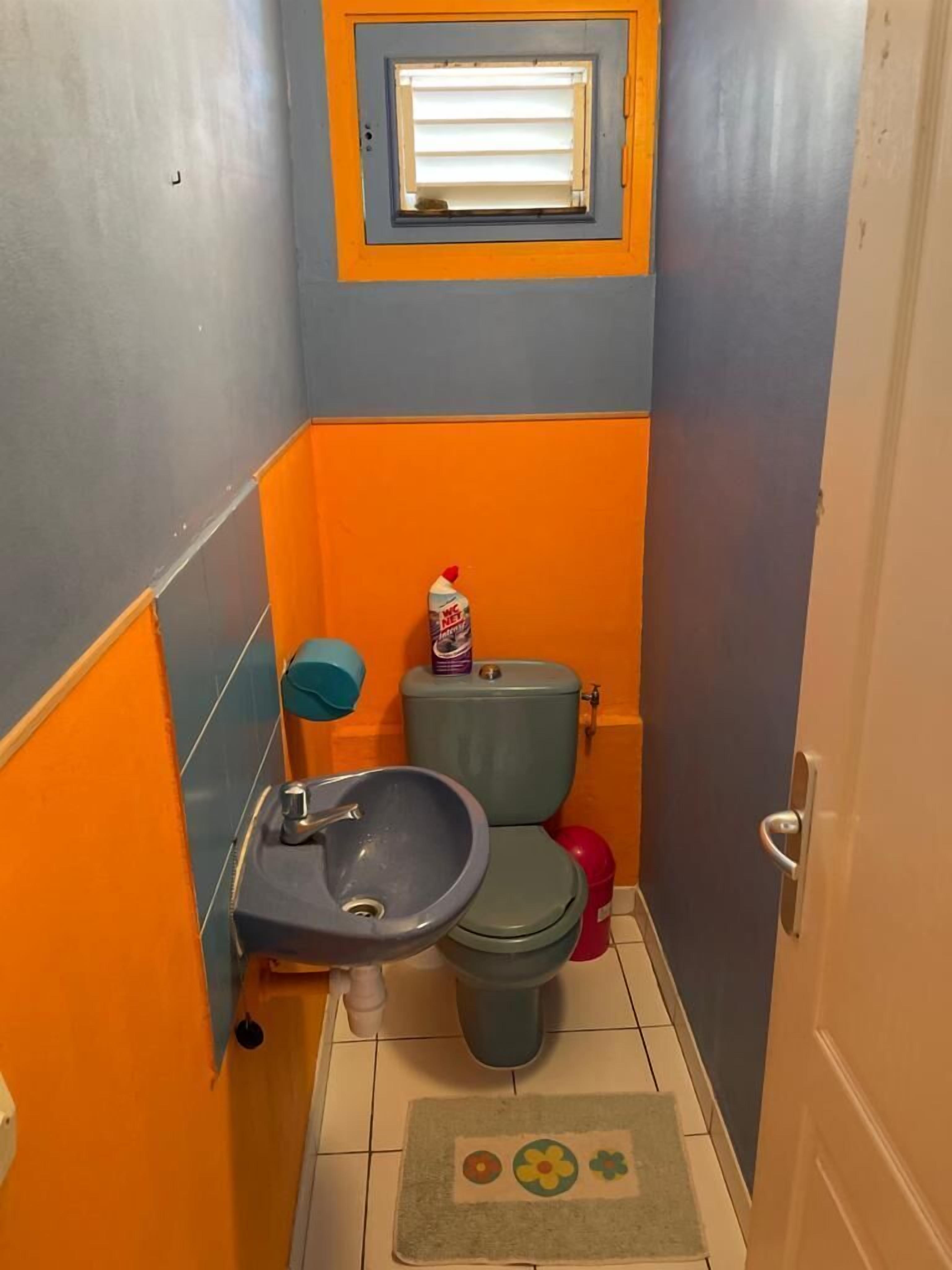 Pieni kylpyhuone, jossa on pesuallas, wc ja ikkuna.
