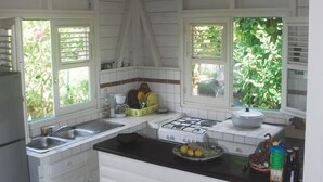 Une cuisine avec des meubles blancs, un plan de travail noir et une cuisinière à gaz.