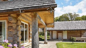 Eine rustikale Blockhütte mit Steinfundament, Holzbalken und einer Veranda.