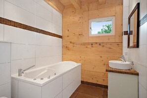 Et moderne badeværelse med træindretning, et badekar, en vask og et vindue med naturligt lys.