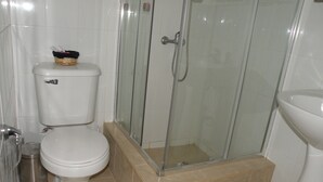Un baño con inodoro, ducha con cerramiento de vidrio y lavamanos.