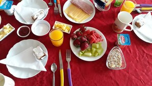 Una mesa de desayuno con platos de comida, cubiertos y una botella de agua.