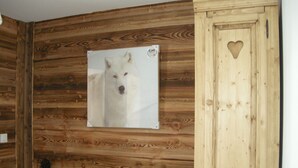 Eine Holzwand mit einem gerahmten Bild von einem Hund, einer Kommode mit Herzförmigem Ausschnitt und einem kleinen Tisch mit einem Buch.