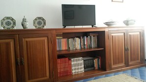 Um armário de madeira com estantes, uma televisão, pratos decorativos e uma tigela.
