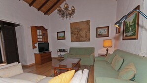 A living room with a television, sofa, armchair, and a painting on the wall.