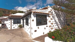 A white building with stone accents, a tiled roof, and a small porch area.