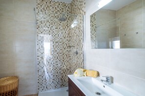 Ein Badezimmer mit Dusche, Waschbecken und Spiegel.