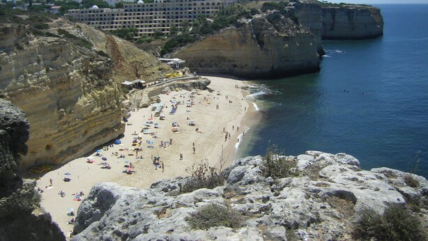 A coastal hotel with multiple floors, a beach, and rocky cliffs. - Apartment Isabel (Carvoeiro)