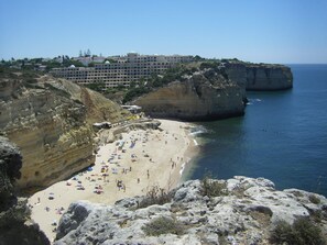 A coastal hotel with multiple floors, a beach, and rocky cliffs. - Apartment Isabel (Carvoeiro)
