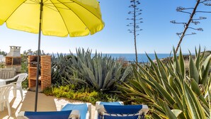 A patio with two lounge chairs, a yellow umbrella, and a view of the sea. - Apartment Isabel (Carvoeiro)