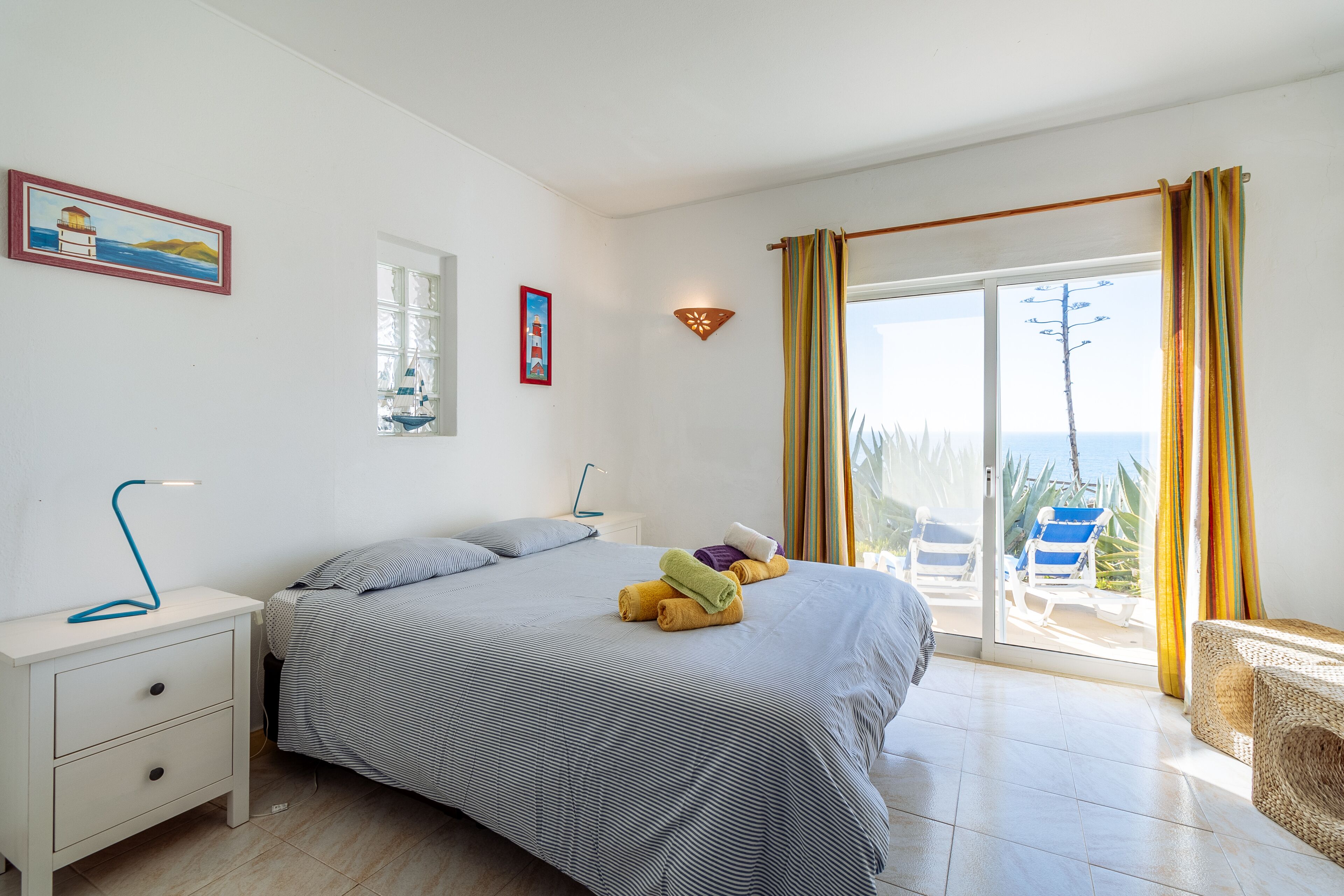 Een slaapkamer met een bed, nachtkastje, lamp en uitzicht.