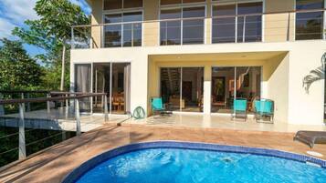 A two-story building with a swimming pool, outdoor seating, and a covered patio area.