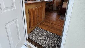 Een moderne keuken met houten kastjes, een eethoek met een tafel en stoelen, en een vloerkleed met een patroon.
