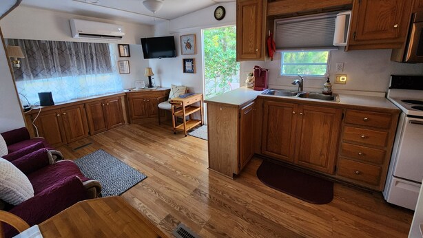 Een kleine camperkeuken met houten kastjes, een spoelbak en een kookplaat.