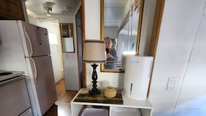 Een compacte keuken met een koelkast, een magnetron en een klein kastje met opbergplanken.