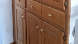 Een houten garderobe met meerdere deuren en lades, voorzien van messing handgrepen.