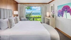 A hotel room with a large bed, a view of the ocean, a balcony with plants, and a painting of flowers. - Hale Luana By Parrish Kauai-beachfront estate with pool (Koloa)