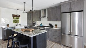 A modern kitchen with granite countertops, stainless steel appliances, and dark wood cabinets.