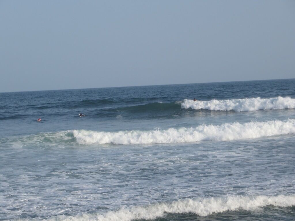 Ein Strand mit Wellen und zwei Schwimmern.