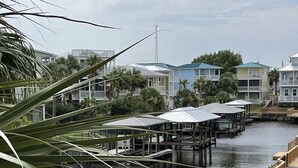 Une propriété située au bord de l’eau, dotée de quais en bois, d’une pelouse et offrant une vue sur les immeubles résidentiels de l’autre côté.