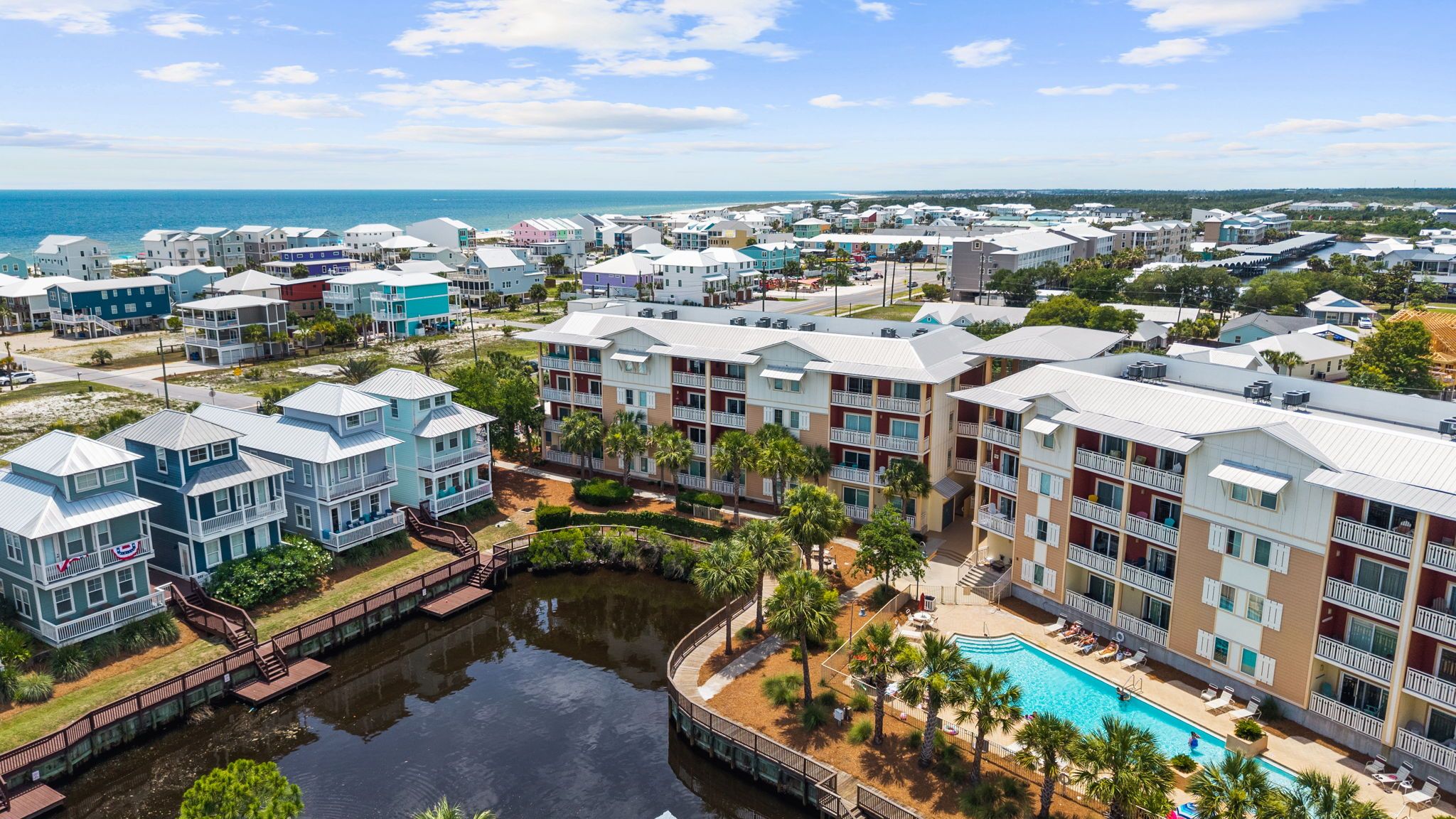 A coastal resort with multiple-story buildings, a central swimming pool, and a marina.