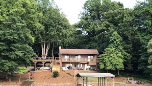 Un chalet au bord du lac, doté d’une terrasse, d’un quai abrité et d’une voiture garée à proximité.