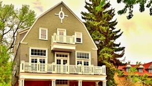 A two-story house with a balcony, a porch with potted plants, and a stone foundation. - The Heart of Manitou Springs. Award-winning. Luxurious. Historic. 1st Floor unit (Manitou Springs)