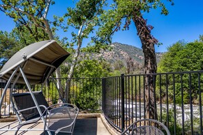 A deck with a canopy and chairs overlooking a river, surrounded by trees and a mountain. - River Oasis with Plenty of Family Fun (Three Rivers)