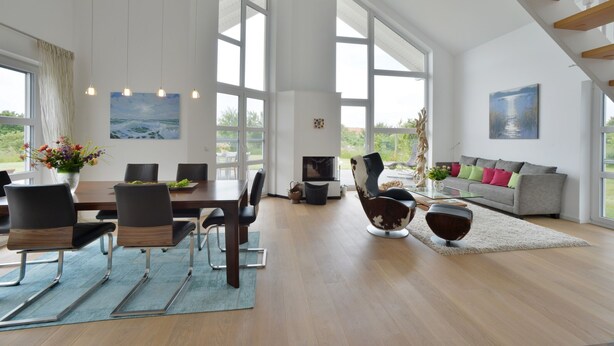 Un vaste espace de vie comprenant une table à manger, des chaises, un canapé et une grande fenêtre donnant sur l’extérieur.