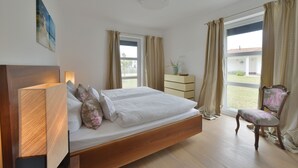 Une chambre à coucher avec un lit, une chaise, une commode et une fenêtre avec des rideaux.