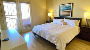 Ein Hotelzimmer mit einem Bett, Nachttischlampen, einem Deckenventilator, einem Gemälde an der Wand und einem Schreibtisch mit Telefon.